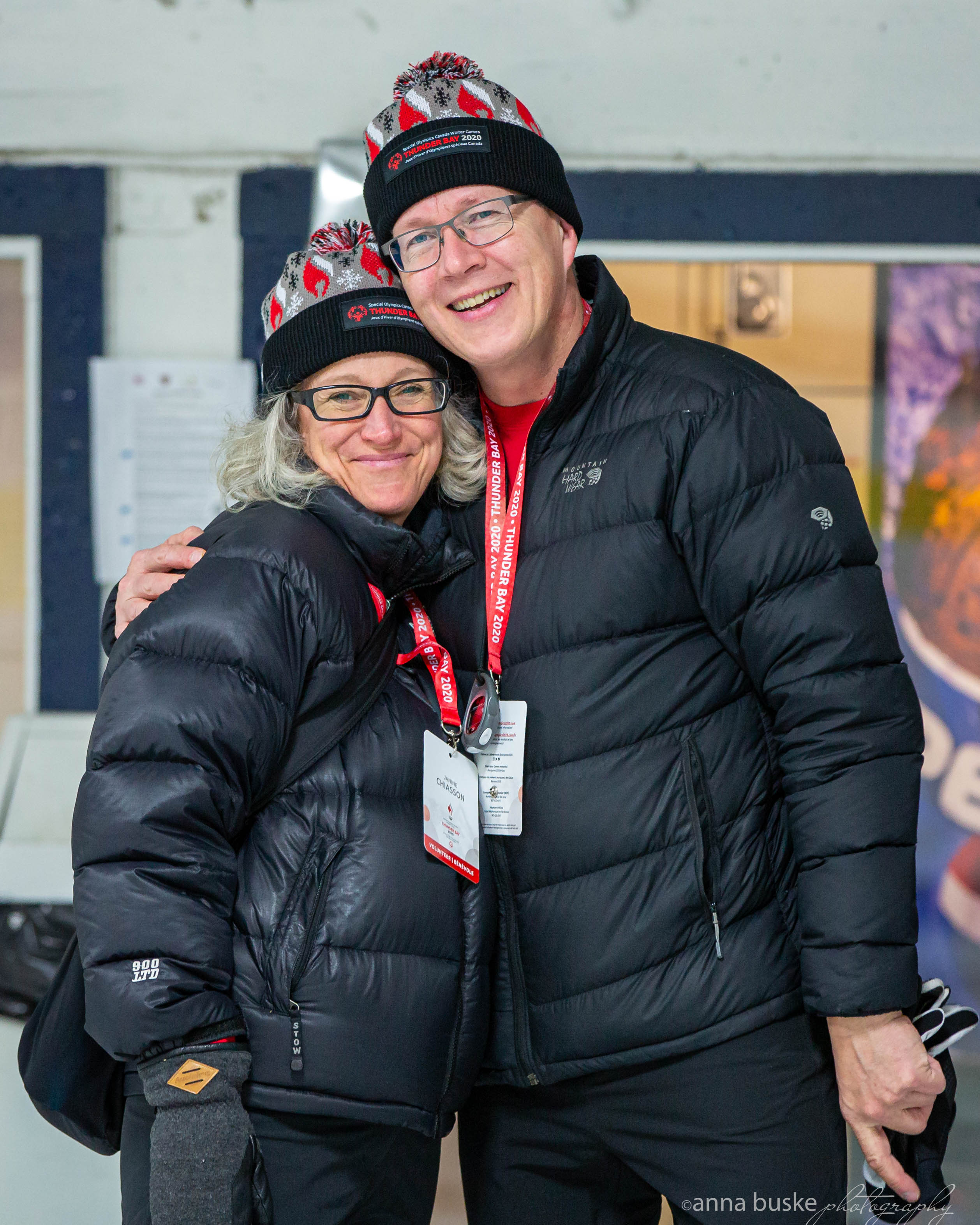 Two people in black winter jackets and Thunder Bay 2020 toques smile at the camera 